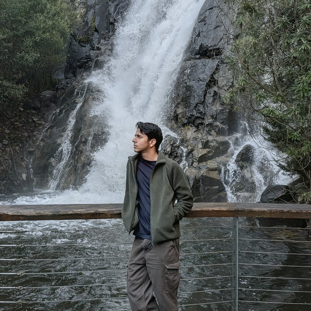 Manish standing by a waterfall